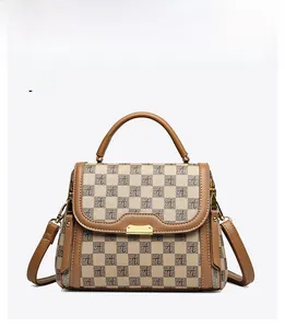 Detail view of khaki handbag with monogram print, golden buckle, and top handle
