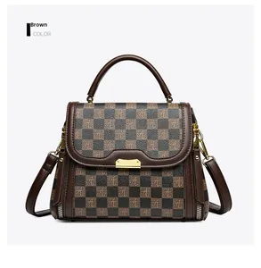 Detail view of brown checkerboard handbag with gold hardware and removable strap