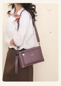 Close-up of purple lychee textured leather crossbody bag with multiple zippers and strap