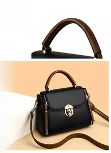 Détail du sac à main en cuir grainé noir avec boucle dorée et poignée bicolore