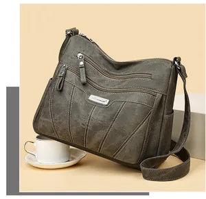 Detail of army green canvas crossbody bag with multiple zipper pockets and top stitching