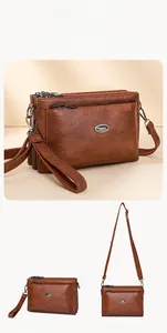 Detail view of brown textured leather bag showing triple zipper compartments and straps