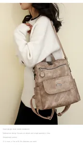 Detail view of a large light brown leather backpack worn by a model against a wall