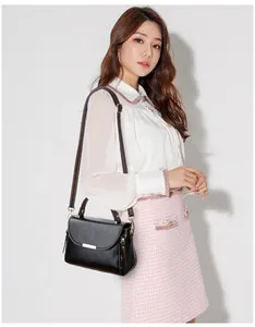 Detailed view of black faux leather handbag with gold metal bar and tassel on female model