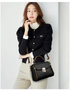 Détail du sac à bandoulière en cuir noir avec fermoir rotatif doré et poignée marron