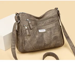 Detailed view of dark brown faux leather bag featuring triple front zippers and silver logo