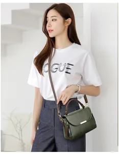 Model wearing dark green leather crossbody bag with brown top handle and gold metal detail