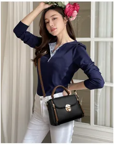 Détail du sac bandoulière en cuir noir avec anses marron et boucle dorée