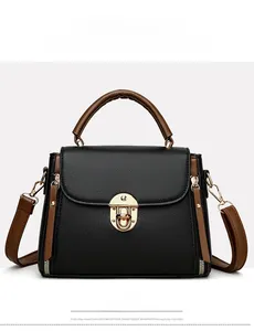 Vue détaillée du sac en cuir noir à motif litchi avec fermoir vintage et poignée marron