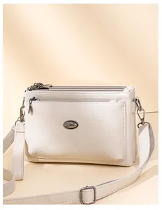 Detail of off-white lychee texture leather handbag with multiple zippers and gunmetal hardware