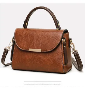 Detailed side view of vintage brown leather handbag with gold metal clasp and top handle