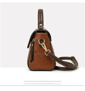 Detail view of the retro brown leather handbag with gold zipper and adjustable strap