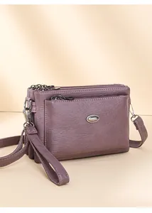 Detail of mauve faux leather crossbody bag showing multi-layered zipper compartments