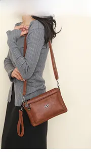 Brown leather crossbody bag detail with multiple zippers and adjustable straps on a model