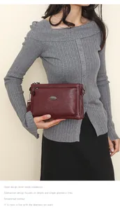 Detail of a dark red soft leather crossbody bag with a metal logo and multi-layer design