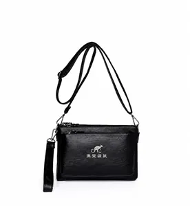 Detalle del bolso de cuero negro de varias capas con logo de canguro y cremalleras