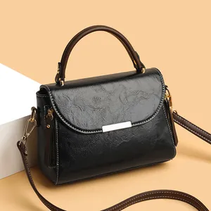 Minimalist black faux leather handbag with brown handles and gold hardware details