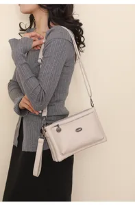 Detail of beige faux leather handbag featuring three-layer zipper and adjustable straps