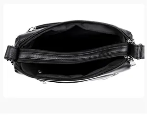 Detailed interior of black leather crossbody bag featuring multiple zipper compartments