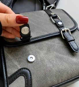 Detail of silver magnetic buckle and grey twill texture on British style messenger bag