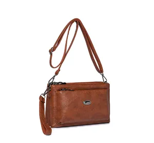 Detail view of brown faux leather shoulder bag with multiple zippered layers and metal accents
