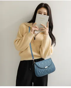 Détail du sac à bandoulière bleu matelassé avec texture plissée et boucle dorée