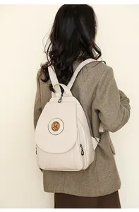 Detailansicht des cremefarbenen PU-Lederrucksacks mit Vintage-Bär-Metallabzeichen