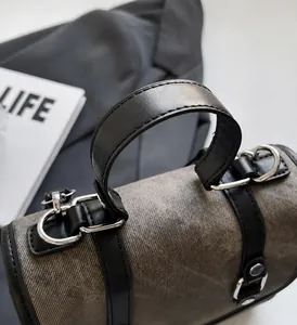 Detail of grey canvas handbag with black leather handle and polished silver D-ring