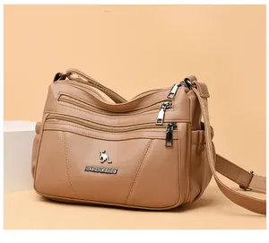 Detail view of khaki crossbody bag with multi-zipper pockets and kangaroo metal logo