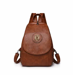 Detail eines braunen Vintage-Rucksacks mit rundem Metall-Bärenemblem und Beschlagteilen