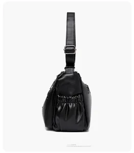 Side view of black pebble leather shoulder bag with pleated side pocket and adjustable strap