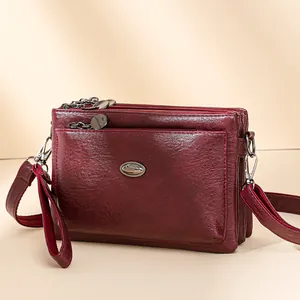 Burgundy multi-compartment crossbody bag with three zippers and soft leather texture
