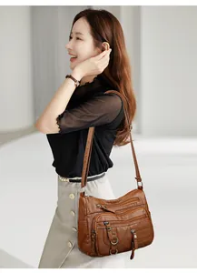 Vue détaillée de la texture en cuir PU marron et des multiples poches zippées du sac