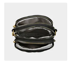 Détail d'un sac bandoulière en cuir avec trois compartiments zippés et doublure chevron