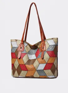 Detalle del bolso tote grande con retazos geométricos multicolores y correa de cuero marrón