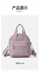 Vista frontal de un bolso de nailon morado claro con bolsillo con cremallera y correa