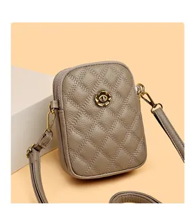Détail de la pochette téléphone en cuir kaki avec surpiqûres losanges et fermoir floral doré