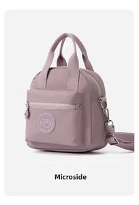 Detalle del bolso de nylon malva con logo Modifei, bolsillo con cremallera y asa de tela