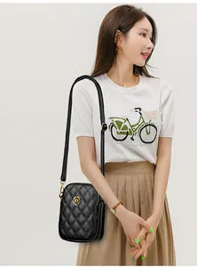 Détail du sac bandoulière en cuir noir matelassé avec fermoir fleur de camélia doré
