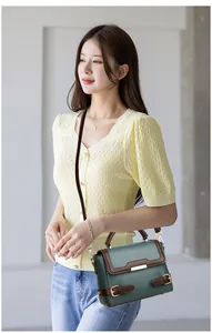 Detail view of dark green pebbled leather shoulder bag with brown strap contrast design