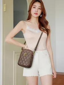 Détail du sac bandoulière en cuir véritable avec surpiqûres losanges et boucle camélia doré
