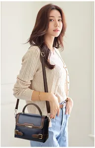 Detail of retro color-block handbag with navy leather and brown strap accents