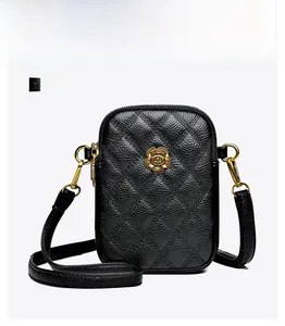 Détail d'un sac à téléphone en cuir noir matelassé avec ornement fleur dorée