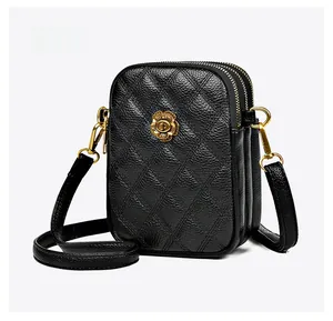 Détail du sac à téléphone en cuir matelassé noir avec fermoir fleur dorée et zips