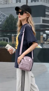 Detalle del bolso bandolera de nailon morado con bolsillo delantero y correa ajustable