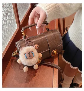 Détail du sac Boston marron vintage avec fermoir doré et accessoire en peluche