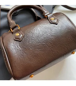 Detailed shot of dark brown Boston bag featuring wrinkled texture and gold rivet hardware