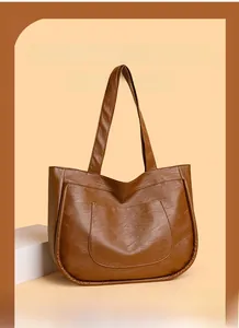 Detail view of caramel brown tote bag featuring textured PU leather and front pocket