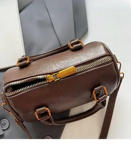 Detailed close-up of smooth gold zipper hardware on a brown leather Boston bag