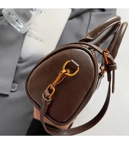Close-up of premium golden metal hardware and brown leather texture on Boston handbag